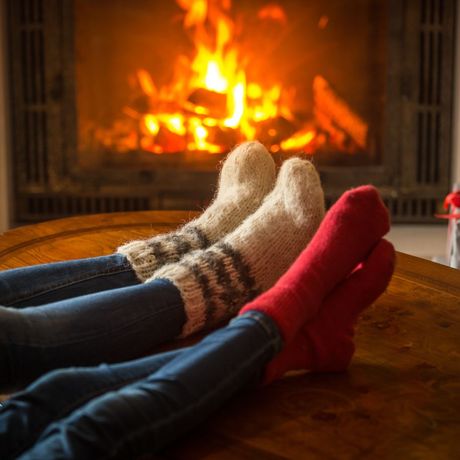 They are wearing wooly socks and jeans, and have one foot crossed over the other